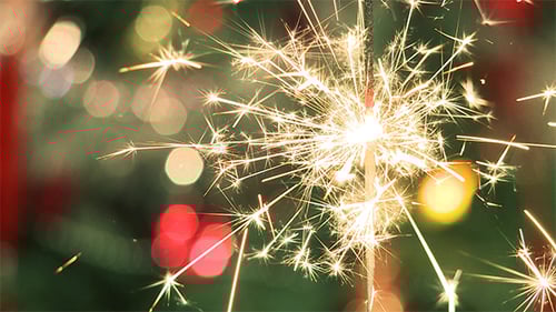 Sparkling Sparkler with Blurry Christmas Lights Background