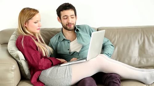 Young Couple Using Laptop on Couch Together