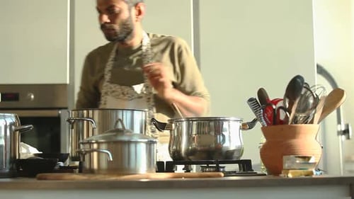 Man Cooking Food in Pot on Stove at Home