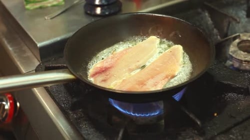 Fish Sizzling in a Pan in Kitchen