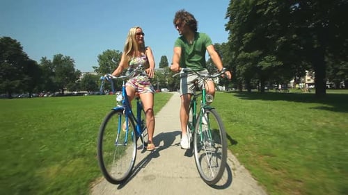 Couple Bicycling Through Green Urban Park on Sunny Day
