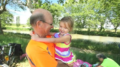 Happy Grandfather Holding Granddaughter Near a Canal