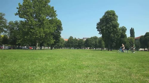 Couple Biking Together in City Park on Sunny Day