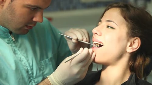 Dental Professional Examining Young Woman's Teeth