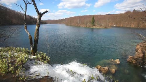 Water Flowing into Beautiful Blue Lake on Sunny Day