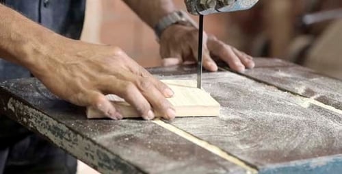 Adult Cuts Wood with Band Saw in Workshop