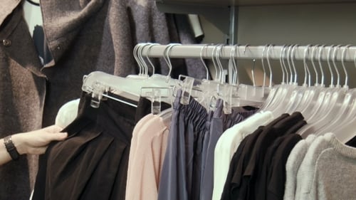 Woman Browsing Clothes on Rack at Clothing Store