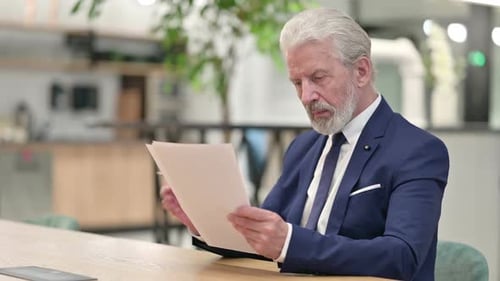 Senior Businessman Reading Documents in Bright Office