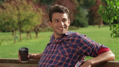 Man With Coffee On a Bench In The Park