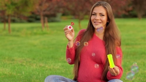 Woman Blowing Bubbles in a Green Autumn Park
