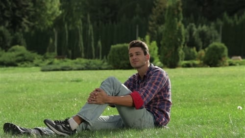 Young Man Relaxing on Green Grass in Park