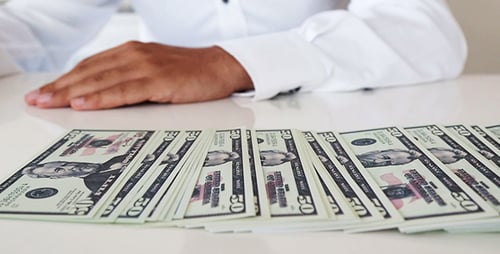 Person Smoothing Fifty Dollar Bills on Table