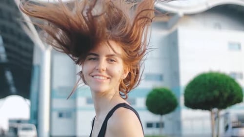 Beautiful Redhaired Woman with Long Hair on Street at Sunset