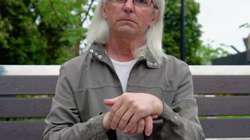 Portrait of Elderly Man on Bench in Public City Park