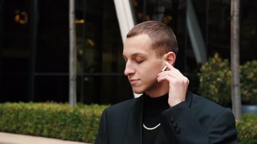 Young Adult Putting in Wireless Earbud Outdoors