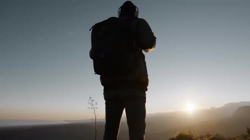 Person with Backpack Standing at Golden Hour Sunrise