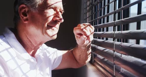 Hombre mayor mirando por la ventana 4k
