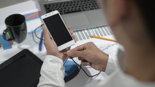 Young Adult Plugs In Smartphone At Desk