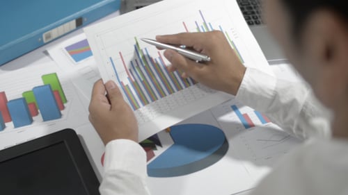 Reviewing Data on Business Bar Graph At Office