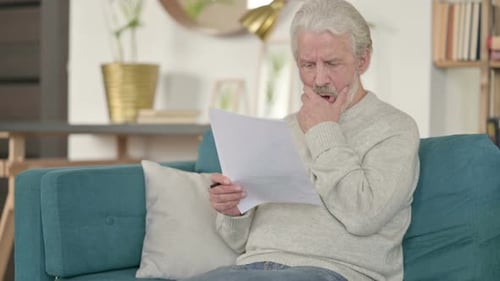 Senior Man Reading Documents Indoors at Home