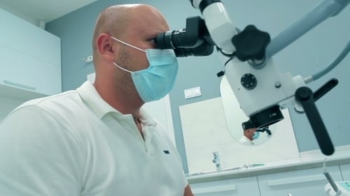 Dentist Using Microscope and Dental Tools in Office