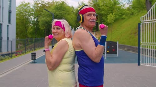 Active Senior Couple Exercising Outdoors With Dumbbells