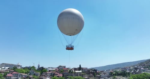 Flying over white balloon in the center of city. Morning cityscape of Tbilisi
