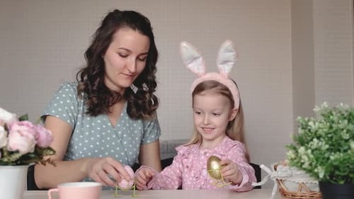 Mother and Daughter Admire Easter Eggs at Table