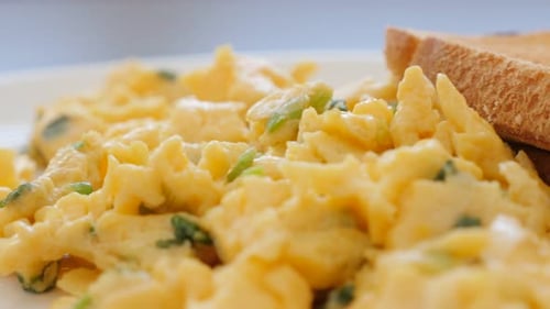 Fried eggs and mixed with scallion on plate slow panning 4K 3840X2160 UltraHD video - Toasted bread