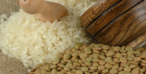 Pile of uncooked rice and green lentils with bowl