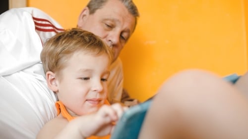 Child and Adult Relaxing Together Using Tablet