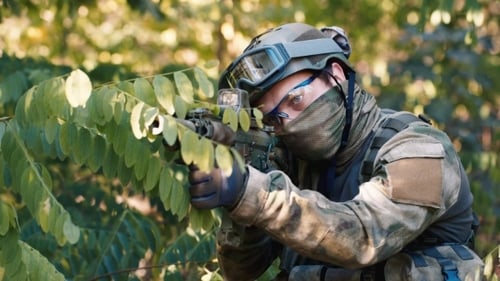 Soldier Aims Rifle in Forest Camouflage Gear
