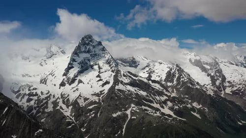 Air Flight Through Mountain Clouds Over Beautiful Snowcapped Peaks of Mountains and Glaciers
