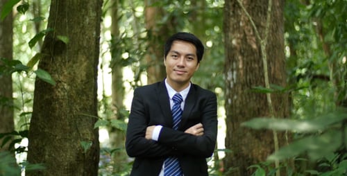 Man in Suit Smiling in Lush Green Forest