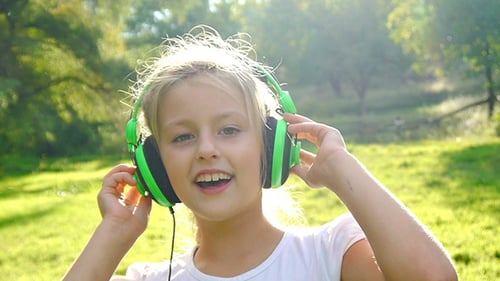 Girl Listening to Music With Headphones in Park
