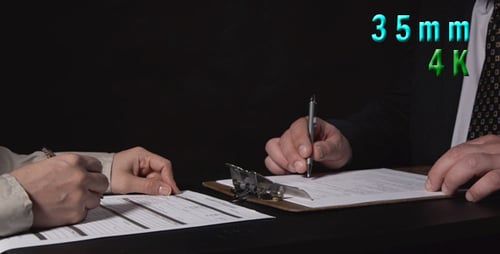 Two People Signing Official Documents at a Table