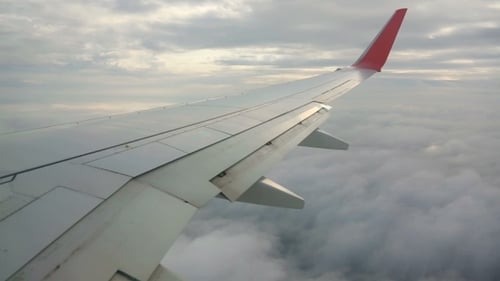 Wing View Over Clouds in Airplane Flight