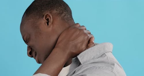 Man Massaging Neck in Pain Against Blue Backdrop