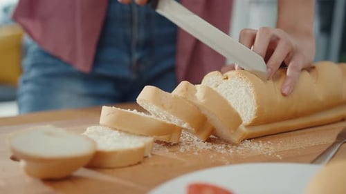 Person Slicing Bread on Cutting Board