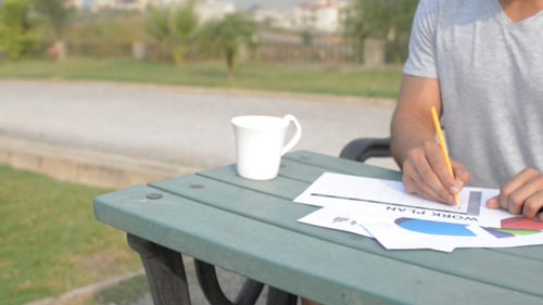 Young Adult Works on a Business Plan Outdoors