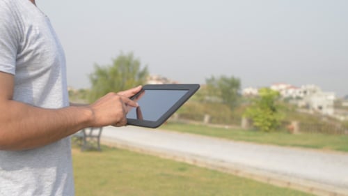 Adult Using Tablet Outdoors in Green Space