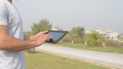 Adult Using Tablet in Green Urban Park