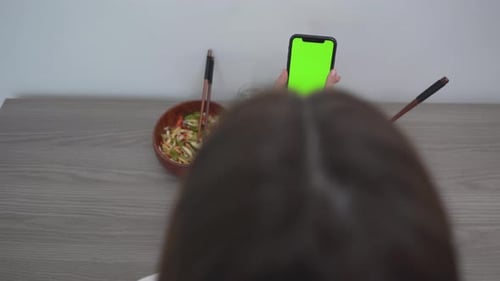 Woman Using Smartphone With Green Screen While Sitting With Food On The Table