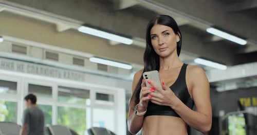 Portrait of Young Woman Using Smartphone at Gym During Workout
