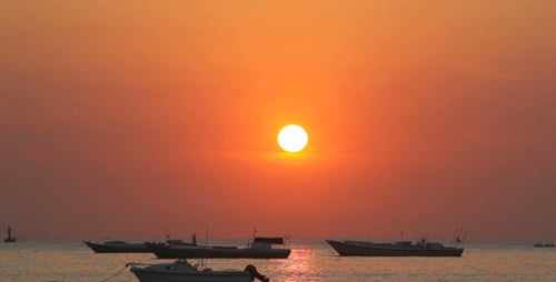 Boats Silhouetted Against a Stunning Sunset Over Sea