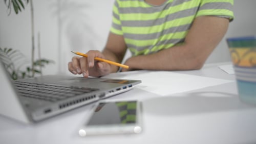 Adult Typing on Laptop and Writing on Paper