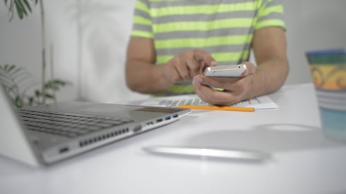 Man Working from Home Uses Smartphone