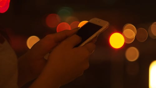 Hands Using Mobile Phone at Night with Bokeh