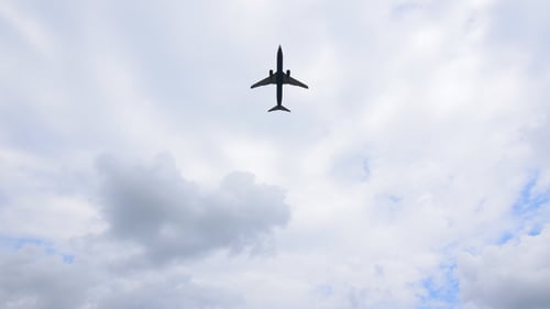 Airplane Flying Overhead Through Cloudy Blue Sky