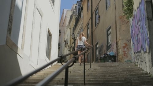 Young Woman Goes Up By Ledder On Street Of Lisbon